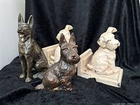 Full view of all items: German Shepherd and Scotty dog figurines in dark bronze finish with two cream-white Scotty dog bookends showing paint wear.