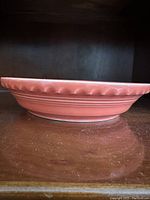 Side profile of the persimmon colored ceramic pie plate showing scalloped edge and ribbed details.