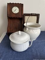 Photo showing the front view of the handmade wooden clock, two ceramic chamber pots, and the antique oak picture frame behind them.