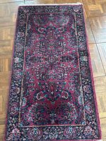 Full view of the Karastan Sarouk wool area rug showing deep wine red base with floral patterns and bordered design.