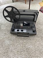 Front angle view of the Kodak Instamatic M80 movie projector showing the large reel spool and front panel controls.