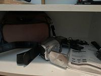 Photo showing the video camera with its carrying bag and cables on a shelf.