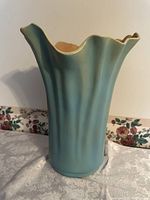 Side view of tall swung vase showing blue-green exterior and scalloped rim