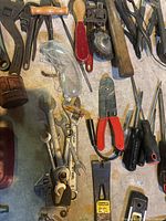Overhead photo showing various hand tools including wrenches, screwdrivers, wire cutters, mallet, and safety goggles spread out on a surface