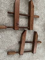 Pair of vintage wooden furniture screw clamps laid out on carpet. Both clamps show wooden screw mechanisms and handles, with visible wood grain and patina.
