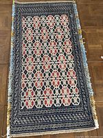 Full view of the woven area rug showing geometric and floral patterns with fringe on one end.