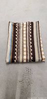Folded vintage blanket throw rug showing multicolor stripe and geometric patterns.