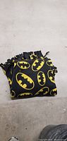 Folded throw rug with yellow Batman logos pattern on black material