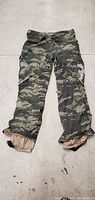 Green camo snow hunting pants laid flat showing front side with brown interior visible at cuffs.
