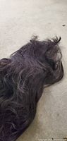 Photo showing the full length of the black synthetic wig on a flat surface, displaying the texture and length.