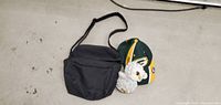 Photo showing all three items including the black pouch, Green Bay Packers hat and the TY Beanie Baby owl plush.