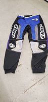 Full view of Thor motocross pants showing front with blue, black, gray and purple panels and large white Thor logos.