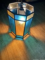 Lit stained glass hanging lamp showing colors and light pattern on wood floor.