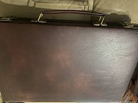 Closed brown leather-like carrying case with metal clasp for the backgammon set