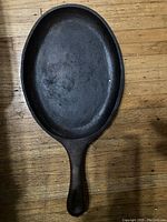 Top view of an oval cast iron pan showing the cooking surface and handle with hanging hole
