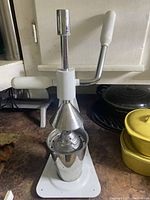 Front view of the manual citrus juicer showing the pressing lever and stainless steel juice container.