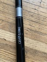 Close-up photo of the pool cue near grip area showing GRAPHSTRIKE branding in white on black.