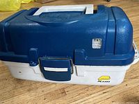 Closed view of blue and white Plano tackle box showing top, handle, and latch.