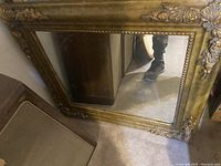 Front angled view of the rectangular mirror showing corner floral carvings and beaded trim on the solid wood frame.