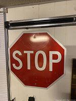 Full view of the stop sign showing its octagonal shape, red background, white text STOP, and mounting hole near the top center.