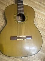 Close-up of the guitar body showing natural wood finish and wear on the surface.