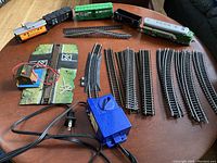 Full view of train set components spread on table including engine, cars, track sections, and transformer