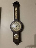 Full view of the vintage wooden wall barometer showing barometer dial, thermometer above, and hygrometer below.