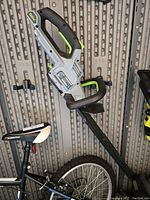 EGO cordless hedge cutter leaning on a bike, showing the upper handle and trigger area.