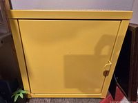 Closed yellow IKEA LIXHULT cabinet with a smooth finish and visible door latch on the side.