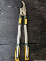 Lopper closed with handles side-by-side, showing aluminum handles and yellow/green grips