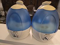 Front view of two blue and white EkoloS humidifiers side by side on a table.