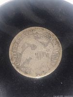 Photo of the reverse side of 1831 US Caped Bust Half Dime showing the eagle with shield and surrounding text.