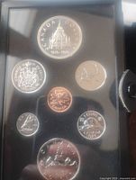 Top view of 7 coins in black presentation case showing the 1976 Double Dollar silver coin, 50 cents, nickel, penny, dime, 5 cents, and 1 cent coins.