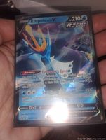 Photo of Empoleon V holographic Pokemon card held in hand, showing card details including abilities and attacks.