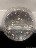 Obverse view of the 1975 Canadian silver dollar coin showing the Voyageur design in a clear plastic capsule.