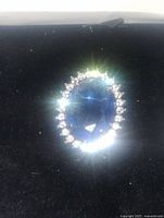 Front view of oval blue rhinestone brooch pendant surrounded by clear rhinestones