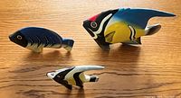 3 hand crafted wooden tropical fish of varying sizes displayed on wooden surface