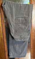 Folded grey Carhartt work pants showing side pocket detail and stitching.