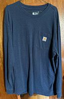 Blue long sleeve tee shirt hanging, showing full front and crew neckline.