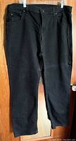 Full front view of black Dickies work pants hanging on clip hanger showing straight leg and general condition.
