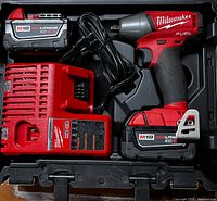 Complete kit in black carry case showing impact driver, charger, two batteries, and power cord.