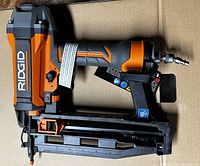 Side view of the Rigid 16 Gauge Straight Finish Nailer showing the orange and black finish with RIGID branding and the air fitting at the rear.