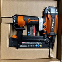 Rigid 18 Gauge Brad Nailer in original cardboard packaging, showing front and side views of the tool.