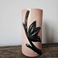 Front and side view of the pink ceramic vase with black floral design against a light background.