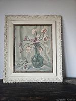 Full view of the framed Harry Lane print with magnolias and monkey figurine on a dark surface against a wall.