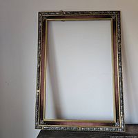 Full view of the rectangular antique frame showing metal floral inlays and velvet inlay inside the border.