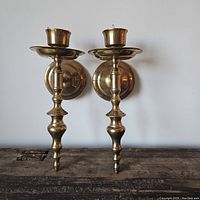 Front view of both matching brass wall sconces showing their design and shape.