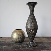 Two brass vases, one round shorter vase and one tall narrow vase with detailed etching