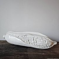 Side view of white ceramic corn sculpture showing detailed kernels and glossy finish.