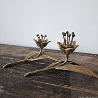 Two vintage brass flower decor pieces shown with detailed leaves and stamens; one flower has some blue stones missing.